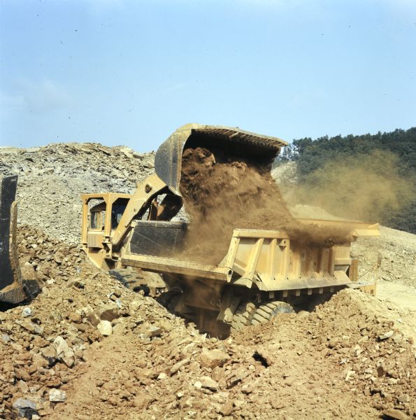 Man operating Pay Loader to dump earth into a Pay Hauler. Vecellio and Grogan, Inc., working on highway project cutting four and one-half miles of Interstate through the rugged terrain of Brushy Mountain.