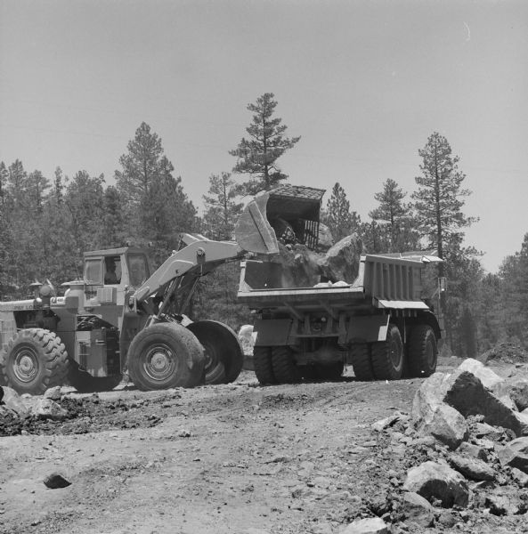 A man operating a Hough Pay Loader is loading material into a 350 Pay Hauler. Morrison-Knudsen Co., Inc. and Gordon H. Ball, Inc., a joint venture have a contract to construct south-bound lane of Interstate 17.