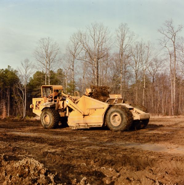 Man operating E 211 Pay Scraper. Caption reads: "Williams Paving Company has contract to reconstruct and relocate 2.686 miles of route US 60 in Newport News."