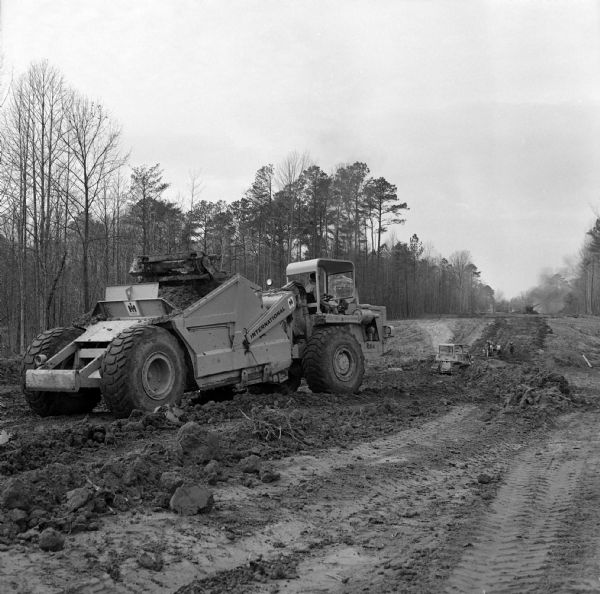 Man operating construction equipment, including a Pay Scraper and Dozer. Caption reads: "Williams Paving Company has contract to reconstruct and relocate 2.686 miles of route US 60 in Newport News."