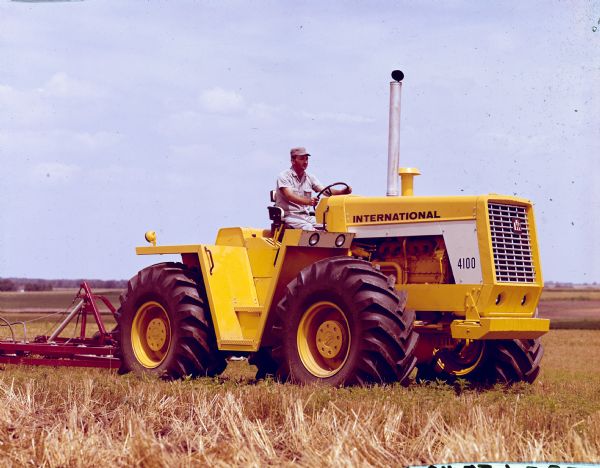 View across field towards a man using a I-4100 tractor in a field.