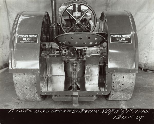 Rear view of tractor. In the background is a cloth canvas hanging as a backdrop. Original caption reads: "Title — 10-20 Orchard Tractor Neg. No. G.P. 11915 Feb 5-37."