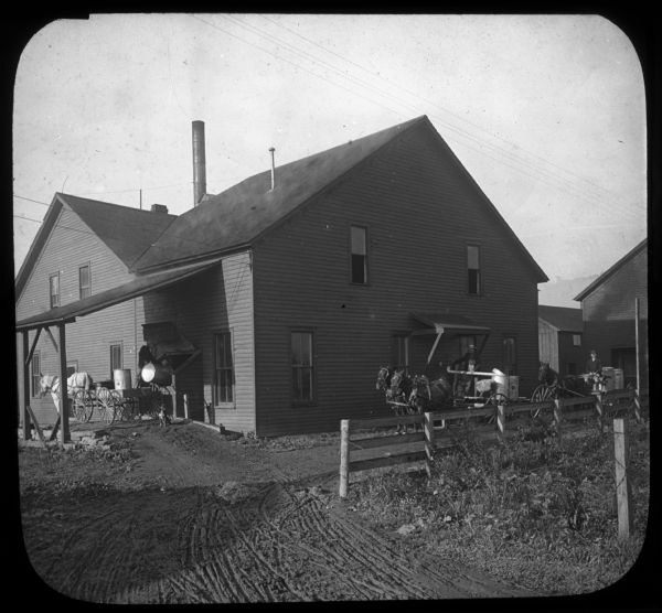 Caption on slide reads: "Delivering the milk at the left hand door, and carrying the skimmed milk away from the right hand door. East Aurora, N.Y." Lantern slide.