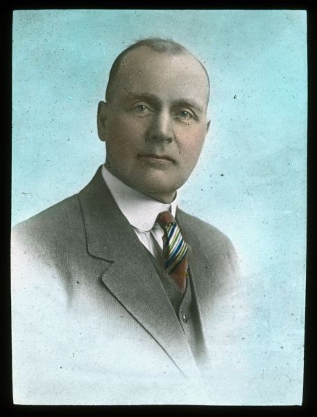 Quarter-length portrait of a man wearing a necktie, shirt, vest and suit coat. Hand-tinted lantern slide.