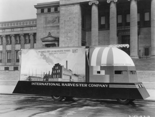 International Harvester Company parade float for the "A Century of Progress" Worlds Fair. This is the front section of the two-section float, and it is parked in front of the Field Museum and reads: "McCormick's First Chicago Reaper Works, 1847, Annual Capacity 500 Reapers."