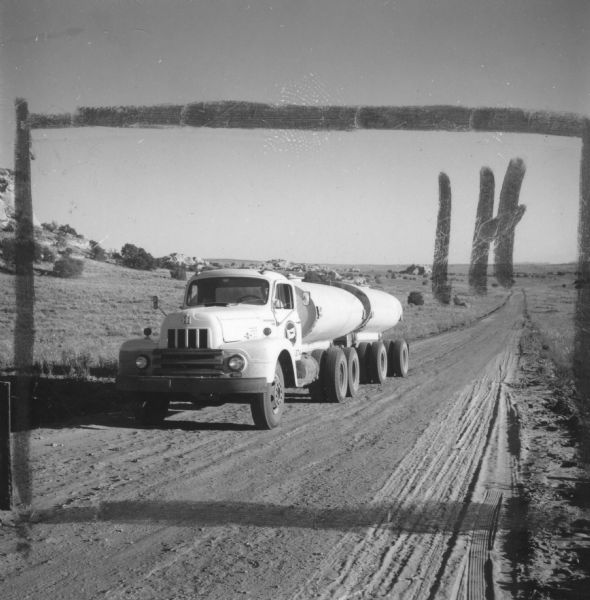 View from front of an International heavy duty truck at Glen Canyon dam site. The truck appears to be part of the R-line. A man is sitting in the driver's seat. Crop marks and "IH" have been drawn on the image.