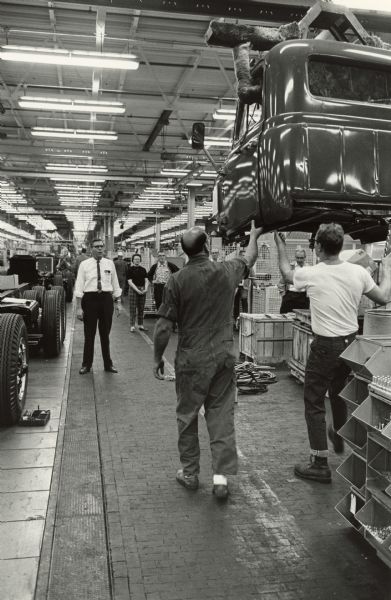 Men working on factory floor with truck body.