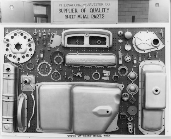 Sheet metal parts displayed on a pegboard. The sign above reads: "International Harvester Co. Supplier of Quality Sheet Metal Parts."