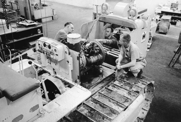 Slightly elevated view of three men working with an experimental crawler tractor indoors. Caption reads: "Experimental Crawler Tractor Equipped with a Turbine Engine."