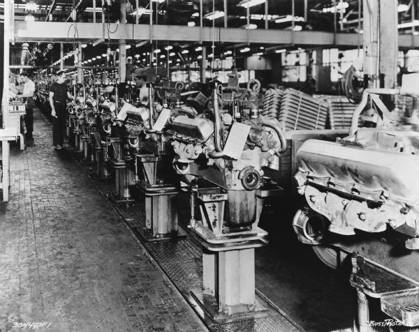 Men are working on a factory floor. Caption reads: "V8 Engine Assembly — Indianapolis Motor Truck Engine Works."