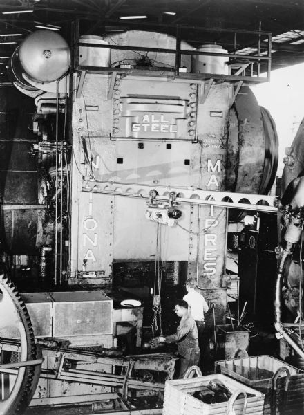 Man are working at the forging machine. The sign on the machine reads: "All Steel, National Maxipress." Caption reads: "Maxipress Forging Machine with Induction Billet Heating Equipment."