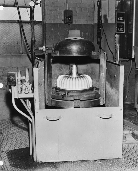 Machinery set up near a wall and an open window in a factory. Caption reads: "Aluminum Torque Converter Centrifugal Casting Equipment."