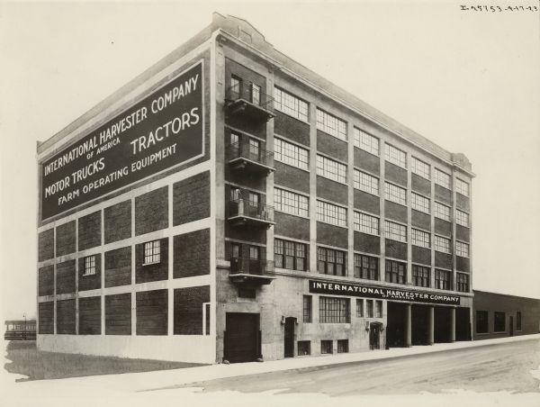 View across street towards the International Harvester's Philadelphia branch house. Railroad tracks and a platform are in the background behind the building on the left. A sign on the side of the building reads: "International Harvester Company of America, Motor Trucks, Tractors, Farm Operating Equipment."