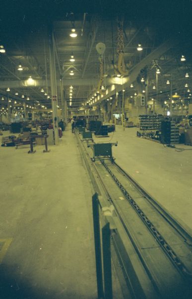 Interior view of plant. A man in the background is working near conveying machinery.