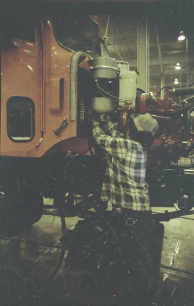 View of a man working near the cab of a truck in the factory.