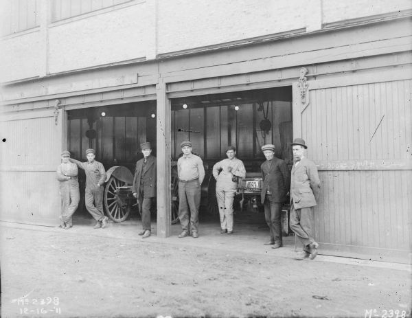 Group of men posing in the open doorway of a garage.