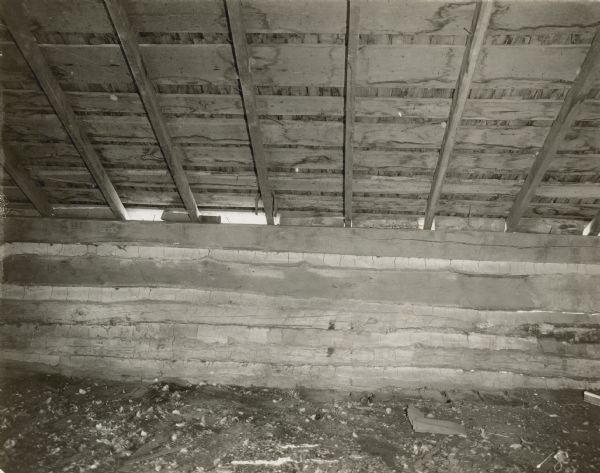 Interior view of log building. There are openings to the outdoors between the log structure and the floor above.