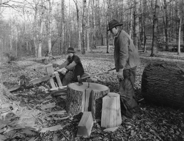 Two men working outdoors making split shingles.
