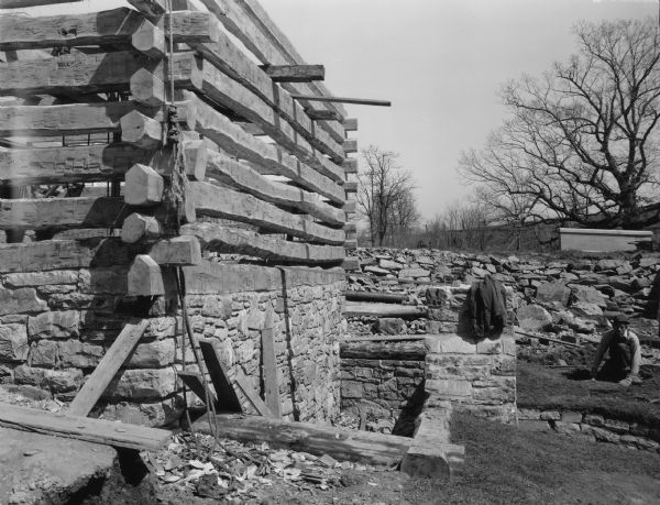 A man is working near the mill. Handwritten on back: "South side of mill showing pit for water wheel."