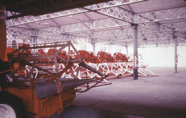 Agricultural equipment in an open sided building. A sign in the center reads: "Défense de Fumer."