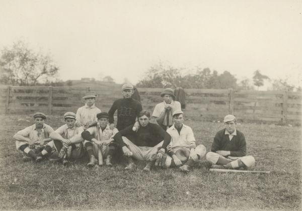 Group portrait of nine boys posing outdoors. Some of them are wearing white shirts with lettering that reads: "S Mc S."