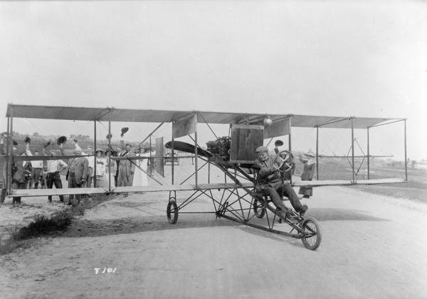 To the accompaniment of a cheering crowd, a pilot in a Curtiss pusher prepares to take off.