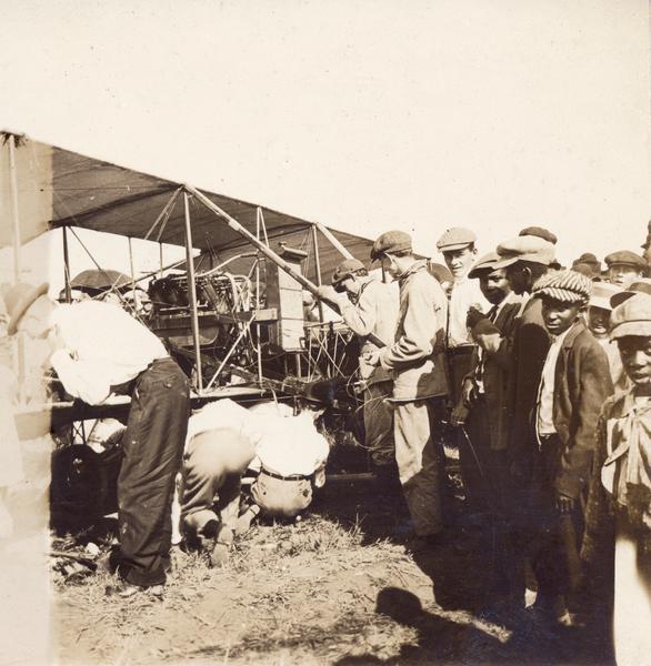 John Kaminski and mechanic Jack Knight making mechanical repairs to Kaminski's plane during an emergency landing at High Point. Such events were guaranteed to draw a crowd of curious onlookers.