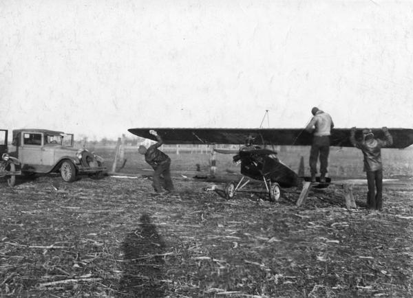 Carl, Robert, and Ray Breecher at work on their modified parasol Heath airplane. After months of hard work, the plane was completely destroyed during a test flight near Waukesha.