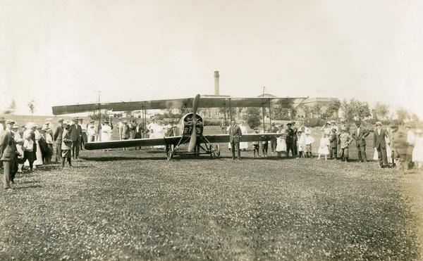 A Standard plane on the golf course of the Waukesha Moor Baths Hotel surrounded by curious onlookers. This landing was representative of the problems encountered by early pilots because of the lack of proper landing fields. In this case a tree had to be cut down to oblige the pilot.