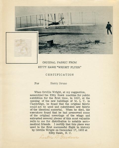 A piece of fabric (approximately 1" x 1") from the 1903 Wright Flyer. It is attached to a certificate and includes a photograph. 

