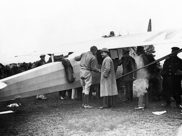 Charles Lindbergh receiving encouragement from an unidentified spectator as the "Spirit of St. Louis" is prepared for take off. Described by some as a flying fuel tank, the Ryan monoplane barely made it off the ground.