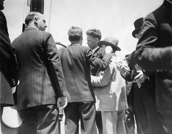Charles Lindbergh on board ship in New York Harbor. After flying to France in the "Spirit of St. Louis," Lindbergh returned to the United States by ship. He was greeted by what was then the greatest reception accorded a single individual in the city's history. Publicist Harry Bruno, who represented Lindbergh on behalf of the Wright Aeronautics Company, the manufacturer of Lindbergh's engine, stands with his back to the camera. Bruno later recalled that Lindbergh "was still amenable to advice. [The] photo shows me with my arm raised, giving the returning hero advice on what he should and should not do."