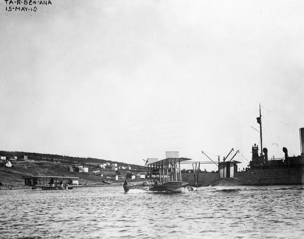 Navy seaplanes NC-1 and (in the foreground) NC-3 at Trepassay Bay, the jumping off point for the first attempt to fly across the Atlantic Ocean. Not in the picture is NC-4, the only plane from this three-plane effort that successfully reached Europe. The naval vessel in the picture was one of a fleet of ships stationed along the route to provide navigational support.