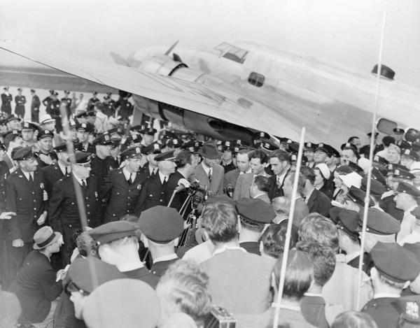 Minutes after finishing their record-breaking flight around the world (in 7 hours and 28 minutes), Howard Hughes and the four aviators who flew with him were mobbed by the public at Floyd Bennett Field in Brooklyn. Hughes is at the microphone; his Lockheed 14-N Super Electra, equipped with two large Wright Cyclone engines, is parked in the background.