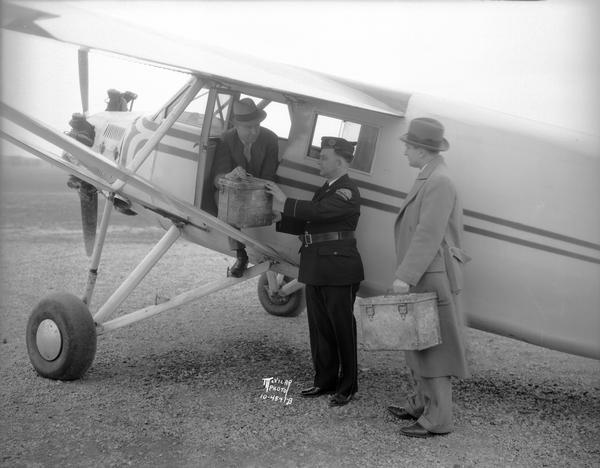 Howard Morey delivering the film "Hell's Holiday" to R.E. Mutchler of American Legion Post No. 57 for Parkway Theatre. (The man in the top coat is unidentified.) Morey flew the film from Milwaukee to Madison so it could be specially screened by the post. The film was billed as "the most authentic and graphic motion picture history of the Great War yet brought to the screen."