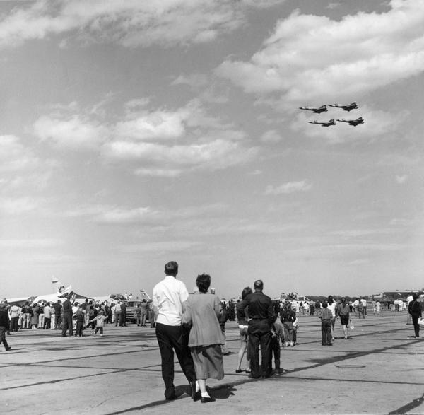 A crowd watching a formation flight by military aircraft at a Truax Field air show.