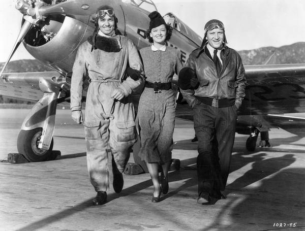 A publicity still featuring the lead actors in "Test Pilot," an MGM 1938 motion picture release. "Test Pilot" was the story of a reckless commercial test pilot (Clark Gable, on the left) forced to choose between aviation and his wife (Myrna Loy). Co-staring with them was Milwaukee-born Spencer Tracy. Usually judged too short and stocky to play the kind of romantic roles in which Gable was cast, in "Test Pilot" Tracy played the loyal mechanic.