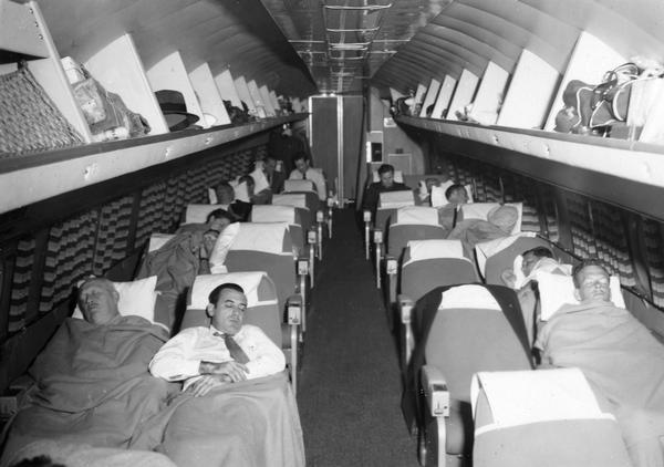 TWA executives napping during a round-the-world flight in a Constellation 803 organized to survey travel conditions in the Far East. The Lockheed Constellation series was first introduced in 1939 and by the early 1950's the Super Constellation represented the pinnacle of commercial airline travel and beauty. However, the propeller-driven Constellations were rapidly replaced by jet engine planes. The album documenting this trip was compiled by TWA publicist Gordon Gilmore, whose papers are available at the Wisconsin Historical Society Archives.