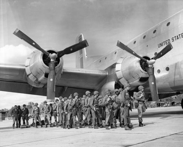 Men of the 57th Infantry Division wait to begin loading on a C-124C "Globemaster II" for transport to their training site. The C-124, a development on the C-47, was capable of carrying tanks, field guns, bull dozers, trucks, or 200 fully-equipped soldiers in its double-decker cabin.