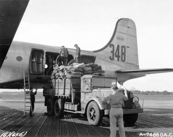 A British soldier directs the truck driver as German workers prepare to load a shipment of coal on a U.S. Air Force C-54 airplane at Fassberg Airfield. From there the coal will be transported to West Berlin. Coal represented 65% of all of the material airlifted to West Berlin. The large C-54s, the military equivalent of DC-4s, were capable of carrying ten tons, and they transported a majority of the goods airlifted to Berlin. The successful conclusion of the airlift represented the first successful challenge of the West to Soviet Cold War expansion. This photograph was part of a public relations program submitted to a PRSA competition by the Military Air Transport Service. MATS supplied much of the aircraft used during the Berlin Airlift.