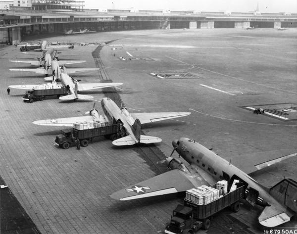 The reason for the official name for the Berlin Airlift, "Operation Skytrain," is suggested by this photograph of C-47 transport airplanes unloading at Tempelhof Air Base.  The airlift began on June 24, 1948 when the Soviet Union cut off all ground traffic to West Berlin.  Generally considered the greatest humanitarian airlift of all time, the Berlin Airlift continued for 15 months.  At its height an airplane took off or landed in West Berlin, around the clock, every 90 seconds.  This photograph is part of a public relations program submitted to a Public Relations Society of America competition by the Military Air Transport Service.  MATS supplied most of the American planes used in the airlift.  The PRSA records are available for research at the Wisconsin Historical Society Archives.