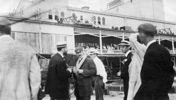 Airplane inventor Glenn Curtiss (with moustache), and his friend and fellow aviator Augustus Post, to his right. Although identified by Warner to 1909, it actually documents a 1910 exhibition at Atlantic City at which both Curtiss and Wright planes appeared. Curtiss is wearing an inner tube/life preserver, as he planned to fly over the ocean.