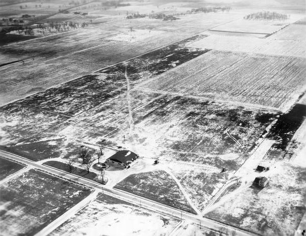 An aerial view of the Oshkosh Airport about three years after Steve Wittman became the manager.  The field was established in 1928 by Oshkosh Airport, Inc. to facilitate air mail service in the Fox Valley.  Since 1969 the airport has been known as Wittman Field, and since 1970 it has been the home of the Experimental Aviation Association.  This photograph was collected by Robert Colton Johnson in conjunction with his administration of various Wisconsin Civil Works Administration projects, 1933-1934.