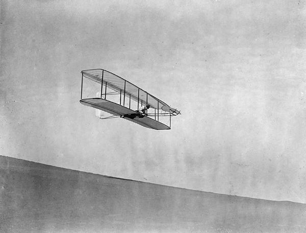 Wilbur Wright gliding down the steep slope of Big Kill Devil Hill at Kitty Hawk, North Carolina. Much of the Wright Brothers' success derived from the fact that they successfully mastered control problems using gliders before attempting powered flight. The original glass negative of this image from the Wright Brothers Collection at the Library of Congress was damaged in 1913. This early undamaged vintage print is from the collection of Arthur Pratt Warner, the first man to fly in Wisconsin. It is not known how Pratt obtained the print, although it is known that he attended several exhibitions in 1910 at which Wright planes were flown. Possibly it was given to Warner at that time.