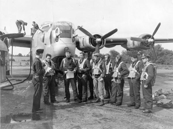 Pilot Robert K. Knowles (second from left) of New Richmond, Wisconsin, and the crew of his B-24 bomber with an interrogating officer at Shipdham, England on D-Day. Knowles later captioned the photograph "Just returning from mission, refueling, and going again."