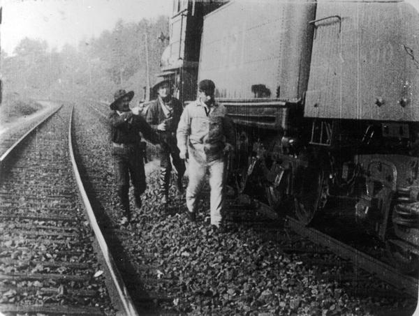 Robbers, guns drawn, escort the engineer from the locomotive in a scene from <i>The Great Train Robbery</i>.