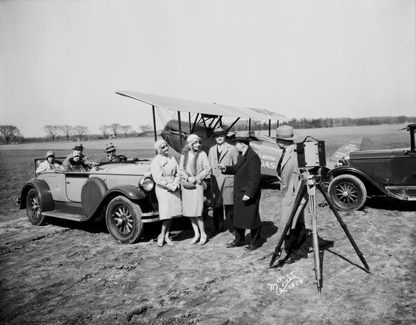Mr. Sutton and Fay directing a scene for the movie "American Girl." Three people are standing in front of an automobile parked next to an airplane at Pennco Field (Royal Airport).