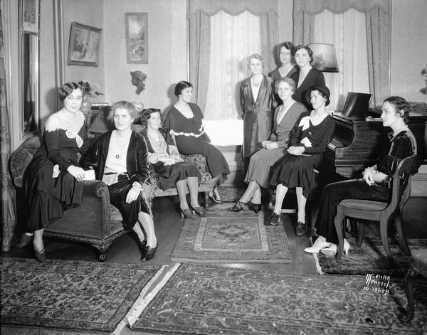 Women posing at Mrs. Emma Ogg's tea party, a benefit for the scholarship fund of the University League, 1715 Kendall Avenue. L-R: Dorothy Fellows, Flora Ritter, Louise Gonce, Margaret Roark, Edna Walker, Katherine Ingrahm, Jane Jones, Esther Gilbert, seated; Helen Twaddell, and Mrs. Rudolph E. ??nger, seated at extreme right.