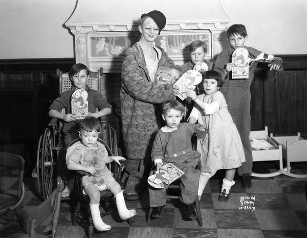 RKO clown "Toto" distributes cardboard Easter bunnies packed with lollipops from the W.T. Grant Company. This event was held in the 2nd floor playroom at U.W. Children's Orthopedic hospital, 436 N. Randall Street.