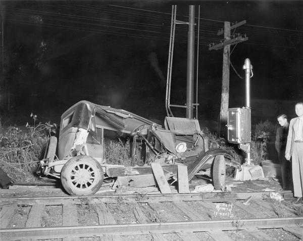 Two men are looking at a damaged automobile belonging to Elmer Meixner, DeForest, after a collision with a Milwaukee Road train at the East Johnson Street crossing.
